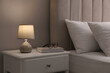 © New Africa - Stylish lamp, book and glasses on bedside table indoors. Bedroom interior elements