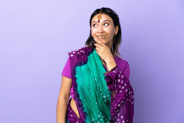 Wall Mural - Indian woman isolated on purple background looking up while smiling