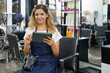 © DragonImages - Portrait of cheerful young hairdresser checking her schedule in application on tablet computer