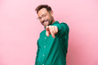 Middle age caucasian man isolated on pink background pointing front with happy expression