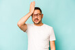 Young hispanic man isolated on blue background forgetting something, slapping forehead with palm and closing eyes.