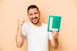 © Asier - Hispanic man holding a beginner driver sign isolated on beige background