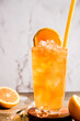 fresh home made orange lemonade or kombucha in tall glass over grey background, healthy eating, detox, wellbeing concept