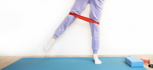 The girl does exercises at home with rubber bands for training, leg exercises, fitness. Sports. Healthy body image concepts