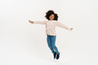 Black preteen girl with curly hair jumping and laughing