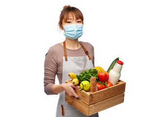 Wall Mural - cooking, health and safety concept - happy smiling female chef in medical mask and apron with food in wooden box over white background