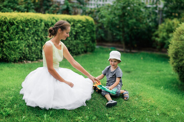 Beautiful woman girl with son boy on the lawn in a beautiful garden. Garden art and a beautiful classic lawn garden