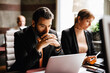 © Maskot - Businessman with hands clasped looking at laptop working by businesswoman at desk in law office