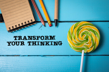 Wall Mural - Transform Your Thinking. Colored candy and office supplies on a blue wooden background