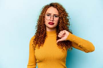 Wall Mural - Young ginger caucasian woman isolated on blue background showing a dislike gesture, thumbs down. Disagreement concept.