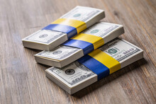 Bundles Of Dollar Bills Tied With The Ukrainian Flag. The Concept Of Support Of The American Government, For The War-torn