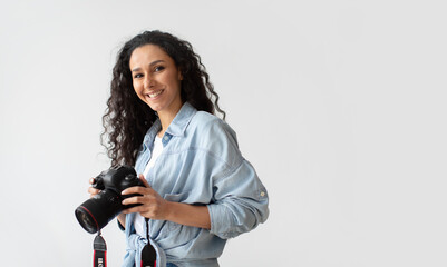 Wall Mural - Photographer Woman Holding Photo Camera Posing Over White Wall