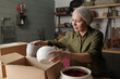 © pressmaster - Contemporary mature female gardener preparing flowerpots for new season for replanting garden flowers while taking them out of box