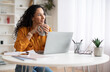 © Prostock-studio - Dreamy Businesswoman Using Laptop And Holding Coffee Cup Indoors