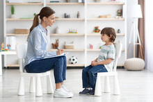 Psychological Consultation For Kids. Side View Shot Of Professional Woman Psychotherapist Sitting Against Little Boy