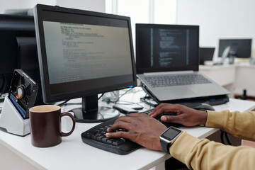 Poster - Hands of young male programmer or it-engineer decoding data on computer screen while pressing buttons of keyboard in office