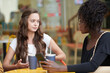 © DragonImages - Serious young woman sharing her problem with friend when they are sitting at cafe table outdoors