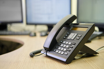 Landline phone on office desk with computer monitors and keyboards