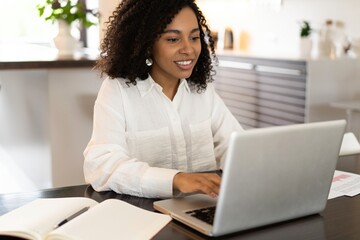 Wall Mural - Confident african american businesswoman working on laptop at her workplace at modern home.