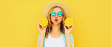 Summer Portrait Of Happy Young Woman Blowing Her Lips With Slices Of Fresh Orange Fruits Wearing Straw Hat, Sunglasses On Yellow Background