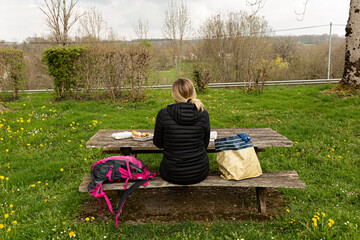 Sticker - Mujer de excursión, comiendo en mesa de madera en el campo.