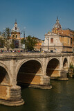 Fototapeta Pomosty - Beautiful view of the Tiber River and the bridge. Green slats along the coast protect from the sun.
