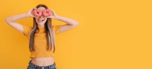 Canvas Print - Funny young woman with tasty donuts on orange background with space for text