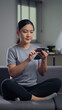 © chajamp - Asian woman sitting on sofa using smart phone and credit card for shopping online at home.