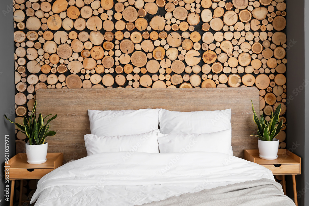 Comfortable bed and nightstands near wooden wall