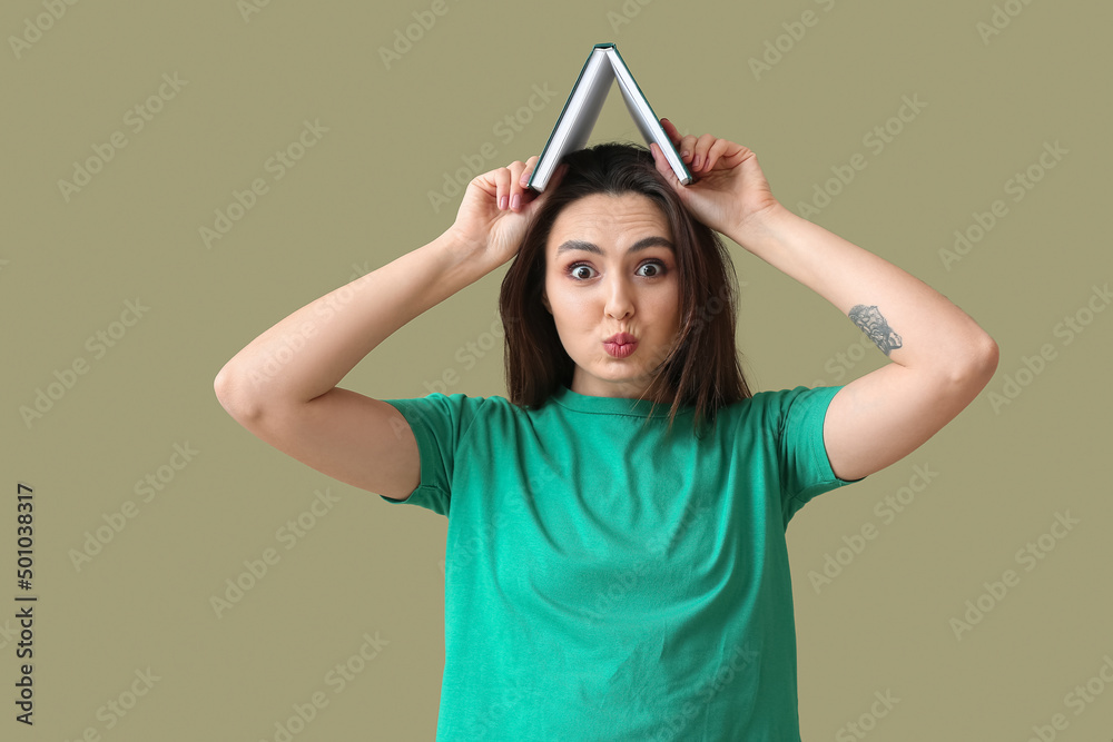 Funny young woman with book on green background