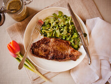 Center Cut Strip Steak With Mixed Greens On A Plate