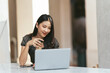 © PaeGAG - Portrait of Asian young female working on laptop and financial report at coffee shop.