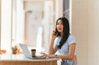© PaeGAG - Asian businesswoman in casual office wear is happy and cheerful while communicating with her smartphone and working in a coffee shop.