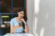 © PaeGAG - Young Asian woman using phone at a coffee shop happy and smile.