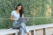 © PaeGAG - Portrait of beautiful Asian woman sitting outdoors at coffee shop restaurant during summer, using smart wireless technology computer laptop and smartphone, relaxing coffee break at cafe restaurant.
