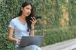 © PaeGAG - Portrait of beautiful Asian woman sitting outdoors during summer, using smart wireless technology computer laptop and smartphone, relaxing coffee break at cafe restaurant.
