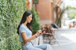 © PaeGAG - Happy asian woman smiling and holding cellphone while sitting in street summer cafe.