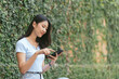© PaeGAG - Happy asian woman smiling and holding cellphone while sitting in street summer cafe.