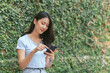 © PaeGAG - Happy asian woman smiling and holding cellphone while sitting in street summer cafe.