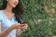 © PaeGAG - Happy asian woman smiling and holding cellphone while sitting in street summer cafe.