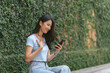 © PaeGAG - Happy asian woman smiling and holding cellphone while sitting in street summer cafe.