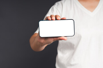 Wall Mural - hand holding a blank screen smartphone while standing on a gray background
