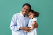 © Pixel-Shot - Portrait of little African-American girl and her father hugging on green background