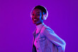 © Atstock Productions - Stylish happy smiling African-American woman wearing headphones and listening to music in modern purple studio background