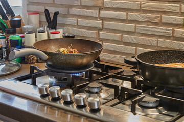 Sticker - Frying pans with fried potatoes, chestnuts, parsley, parmesan on gas stove in the kitchen. Step by step recipe