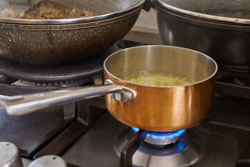 Poster - Saucepan with handle from copper and stainless steel on gas stove fire