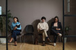 © AnnaStills - Young job candidates sitting on chairs in waiting room and filling forms before interview