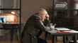 © AnnaStills - Mature man using his mobile phone at table while waiting for interviewer during job interview