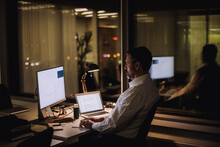 Businessman Typing On Computer Keyboard While Working In Office At Night