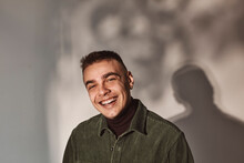 Portrait Of Young Man Laughing Against White Background